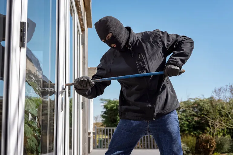Burglar Or Thief Breaking Into A Home Through Window With A Crowbar