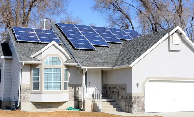 Suburban house with blue solar panels on the roof and a white garage door