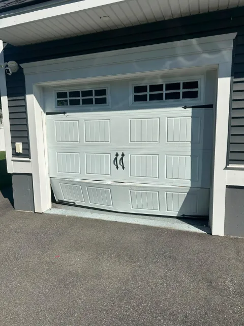 Damaged bottom garage door panel before replacement in Burlington, MA