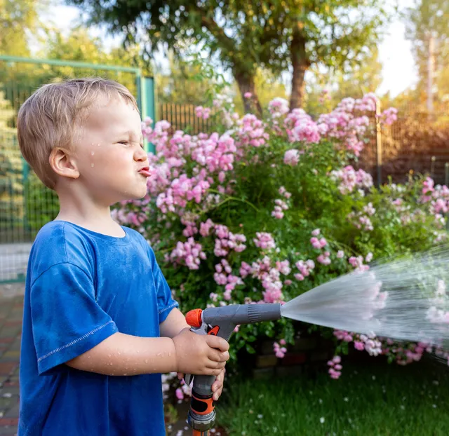 Young Boy watering new lawn installation done by Dracut Landscaping who services Chelmsford Tyngsborough