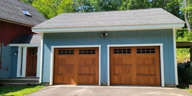 Blue garage with two brown garage doors and a brown entry door, gray roof.