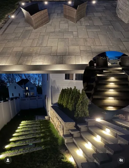 Illuminated stone patio with custom pavers and landscape lighting at night