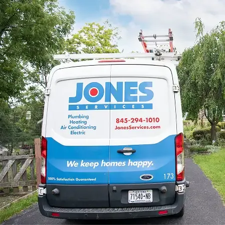 A white Jones Services van, parked on a driveway, displays company branding and contact information for plumbing, heating, air conditioning, and electric services within the local service area.