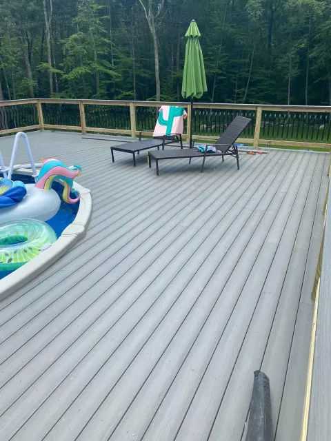 a deck with a pool , chairs , umbrellas and a fountain .