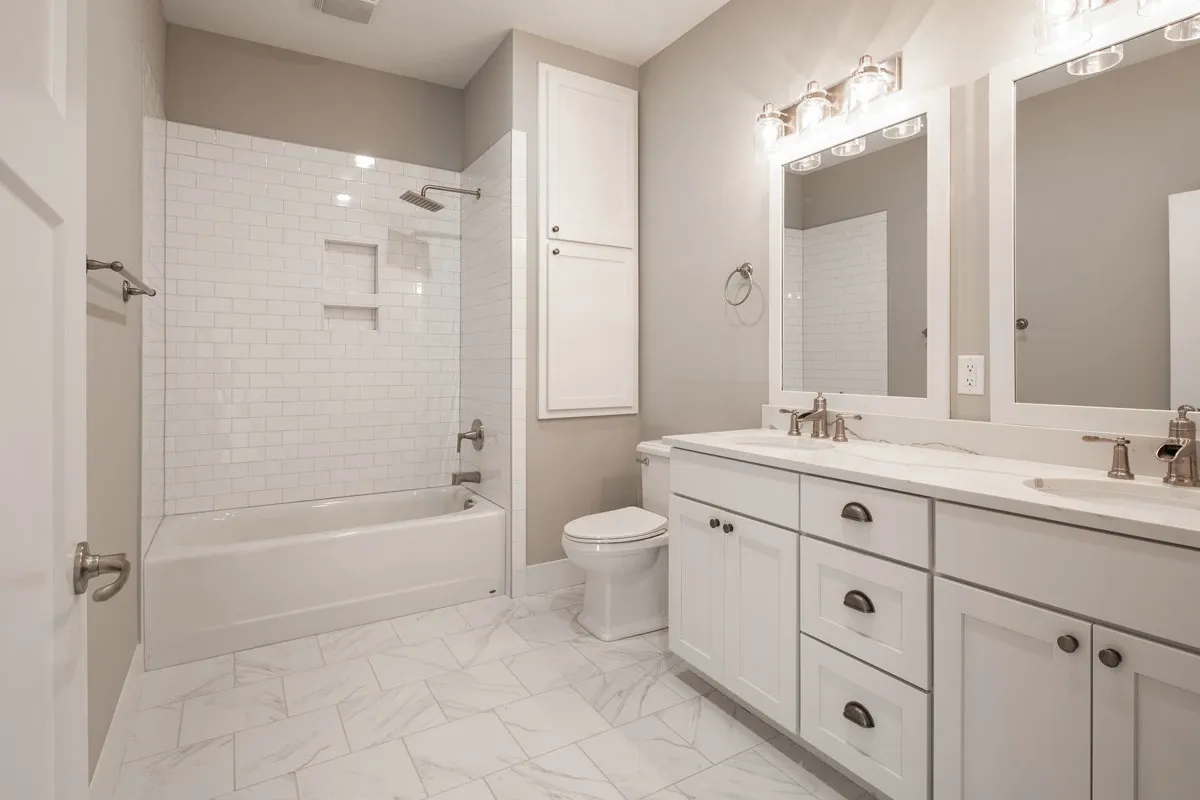 White subway-tile bathroom with a double vanity and soaking tub.