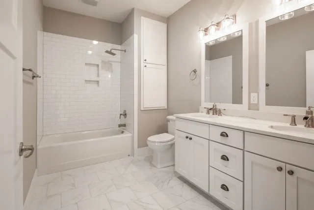 White subway-tile bathroom with a double vanity and soaking tub.
