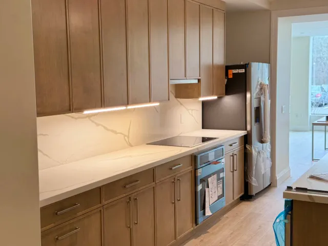 A completed custom kitchen cabinet installation featuring natural wood grain finishes and under-cabinet LED lighting elements.