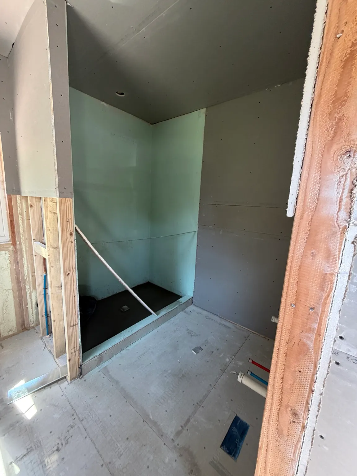 Bathroom and walk-in shower during drywall and waterproofing work