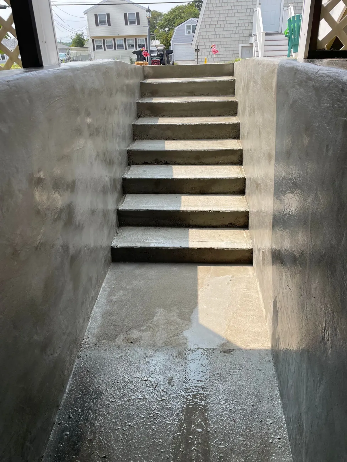 A concrete outdoor staircase leading up from a basement or sunken walkway between two high concrete walls.