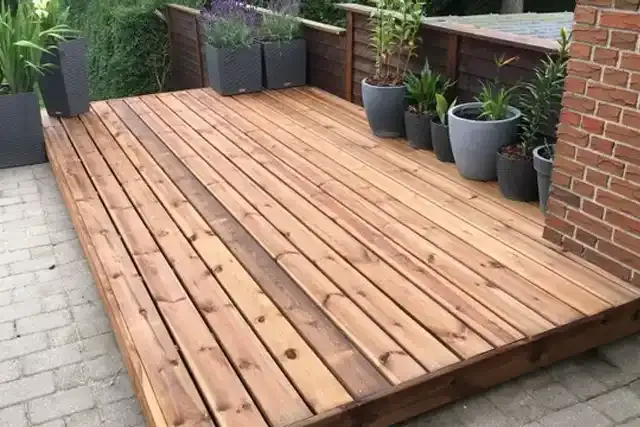 Wooden deck installation featuring smooth planks and decorative potted plants, showcasing expert craftsmanship and enhancing outdoor space aesthetics.
