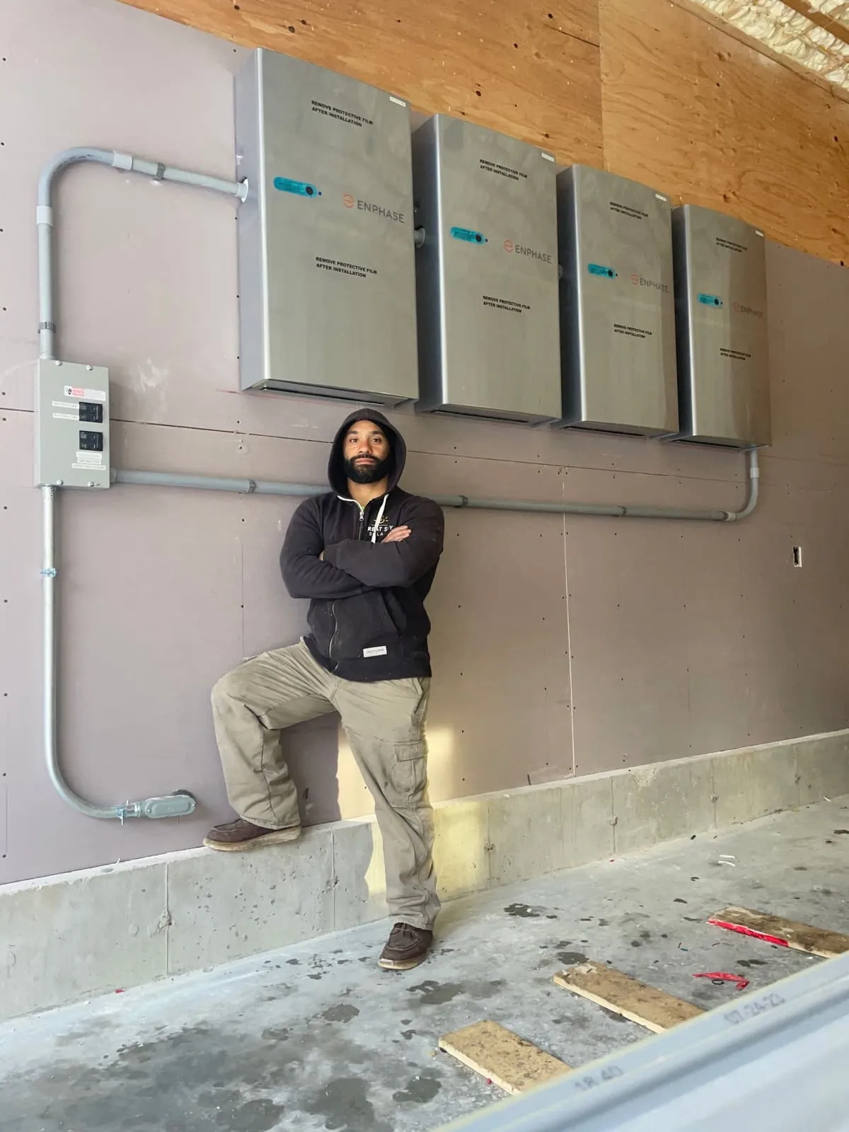 Micah Gentile, owner and licensed electrician at Powered Up LLC, standing in front of Enphase battery backup installation
