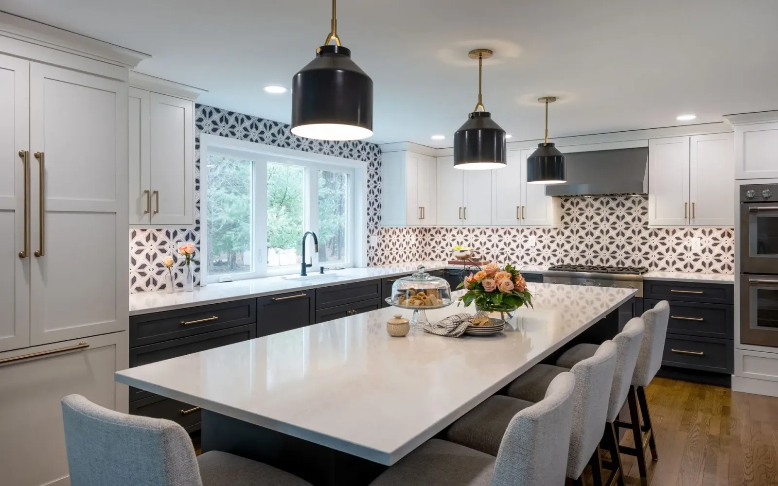 Modern white kitchen with black island, pendant lights, and large window over the sink