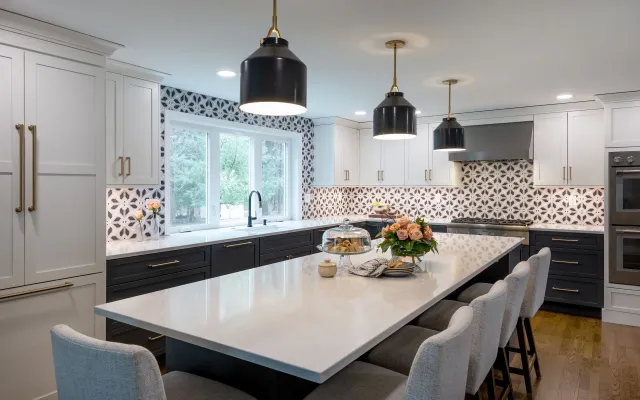 Modern white kitchen with black island, pendant lights, and large window over the sink