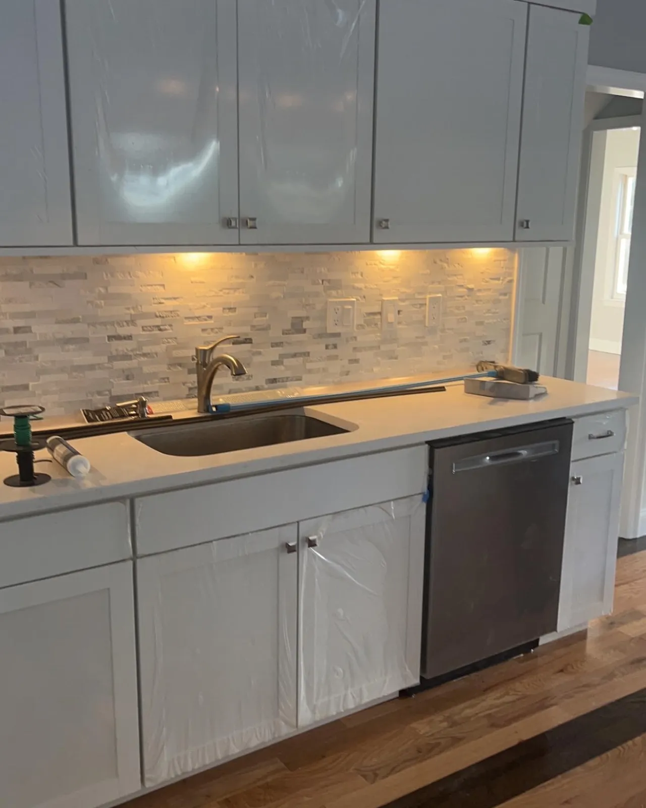 Bright remodeled kitchen with white cabinetry and stone backsplash