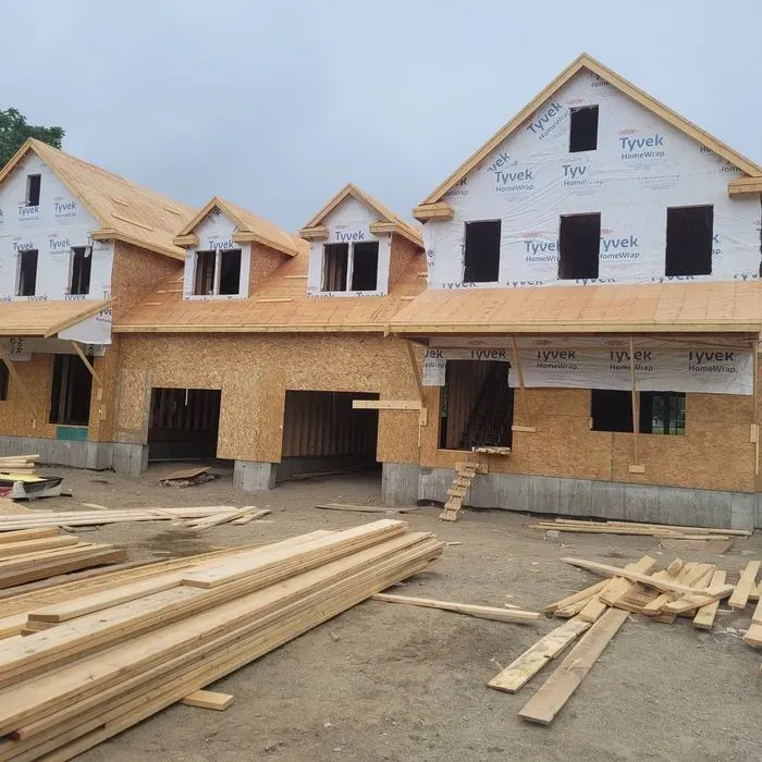 New houses under construction with exposed wood framing and building materials in front