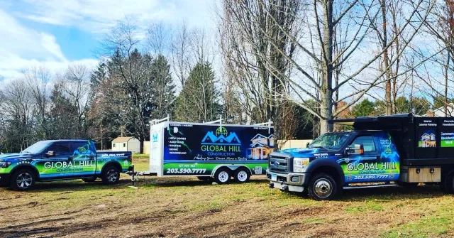 Global Hill Construction trucks and equipment trailer parked at a Connecticut job site