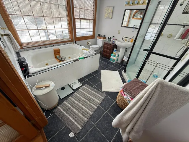 Bathroom before renovation — dated dark tile and jacuzzi tub