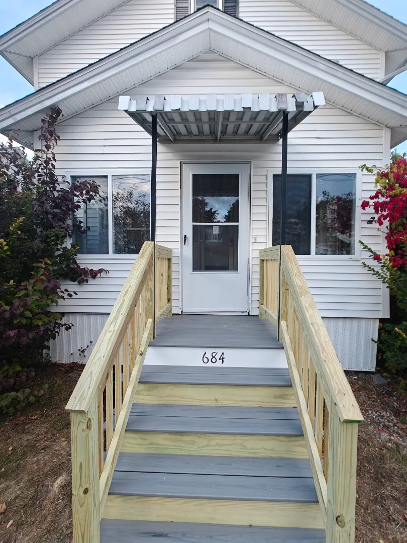 Front steps after rebuild with fresh railings and clean finish