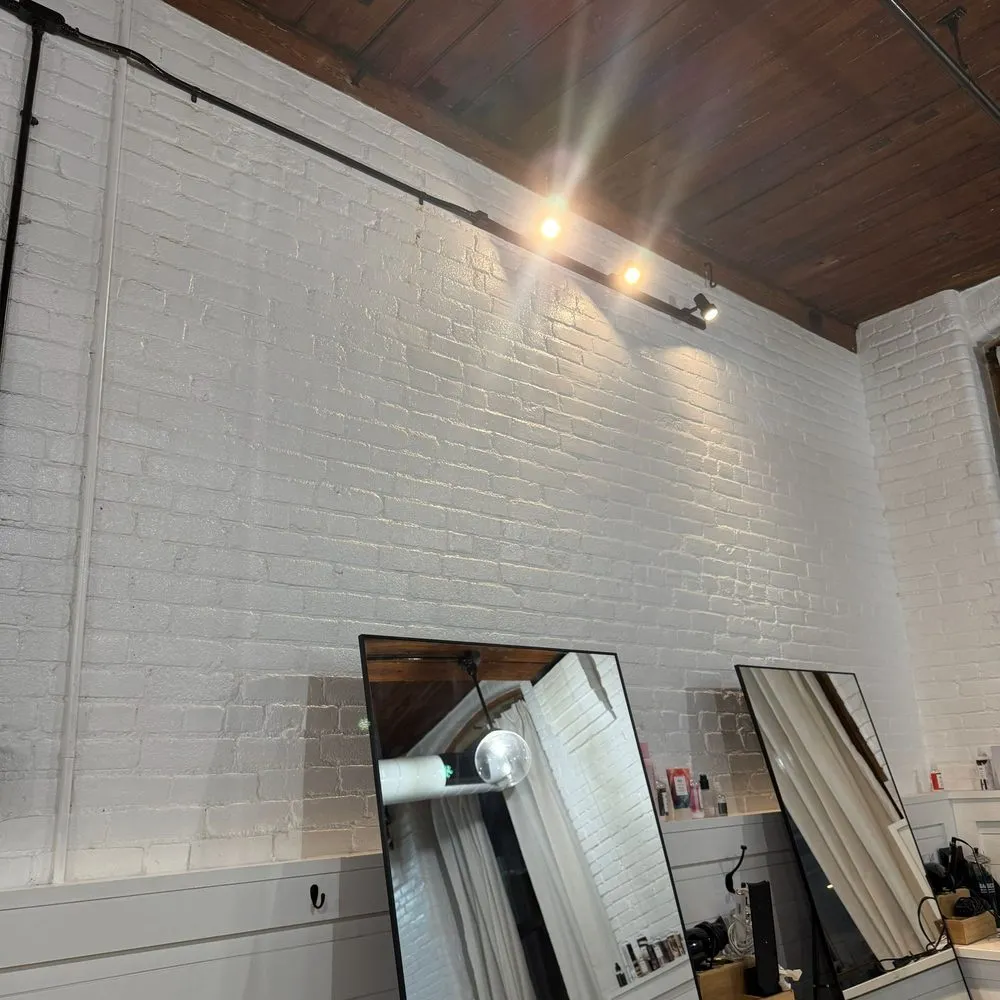 Boston Light & Power electrician installing wall sconce lighting in a salon in Quincy, MA.