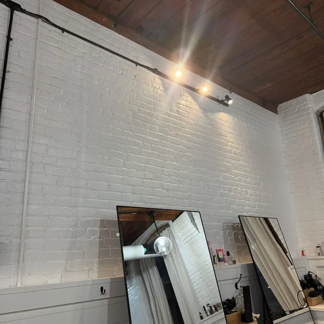 Boston Light & Power electrician installing wall sconce lighting in a salon in Quincy, MA.