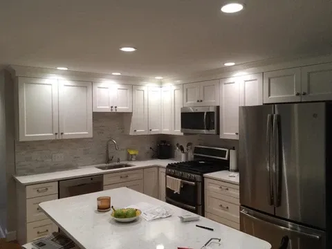 White kitchen with shaker cabinets, stainless steel appliances, and island.