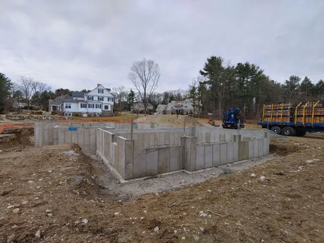 A large concrete foundation is being built in a dirt field.