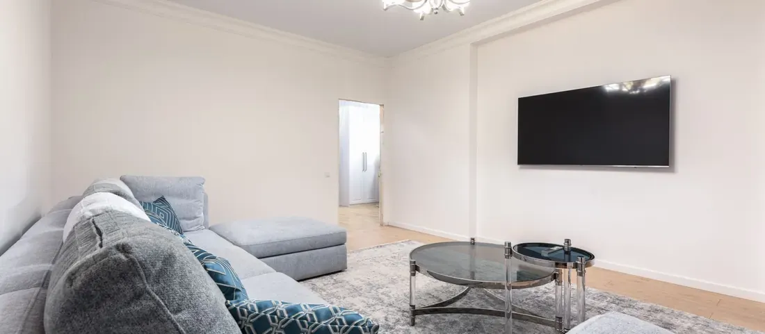 Show ready living room with a grey sectional, rug and wall mounted TV