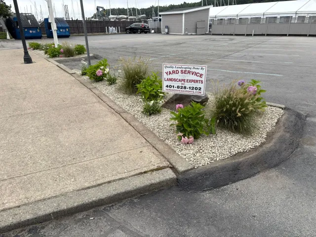 Flowerbed with sign in a parking lot.