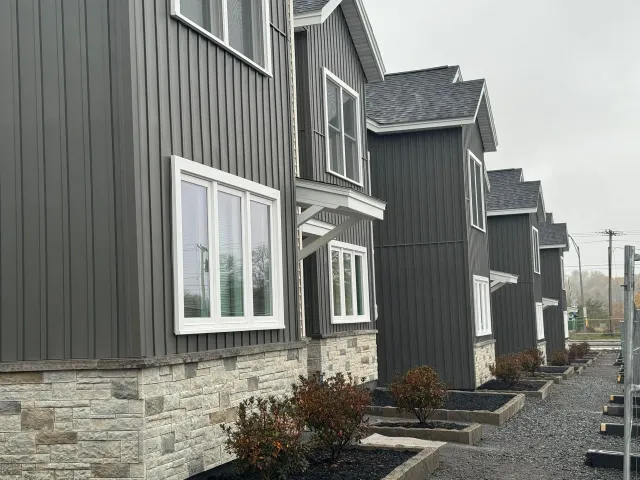 a row of new construction multi family houses with grey siding and white windows