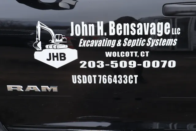 Close-up of John H. Bensavage LLC branding on RAM truck door — JHB logo, phone number, and USDOT number