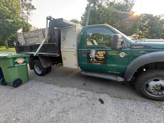 Green Ford F-550 dump truck displaying the Jacko’s Junk Removal logo