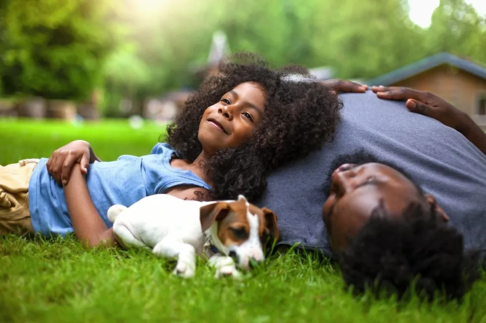 father, daughter and dog in yard