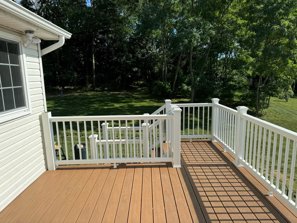 Wooden deck with white railings and stairs to a grassy yard