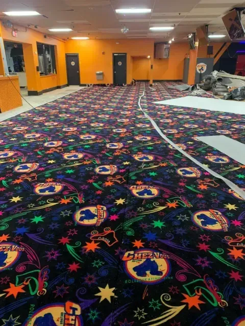 Roller rink interior with patterned carpet, orange walls, and doorways.