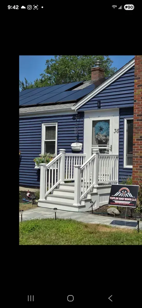 Blue house with white trim, front porch steps, and a small sign in the yard.