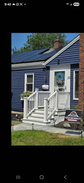 Blue house with white trim, front porch steps, and a small sign in the yard.