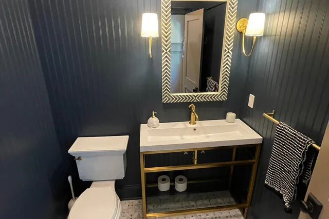Dark bathroom with vertical wall paneling and a custom vanity — Newtown, CT