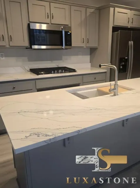 Kitchen with white marble countertops, gray cabinets, stainless steel appliances, and a central island.