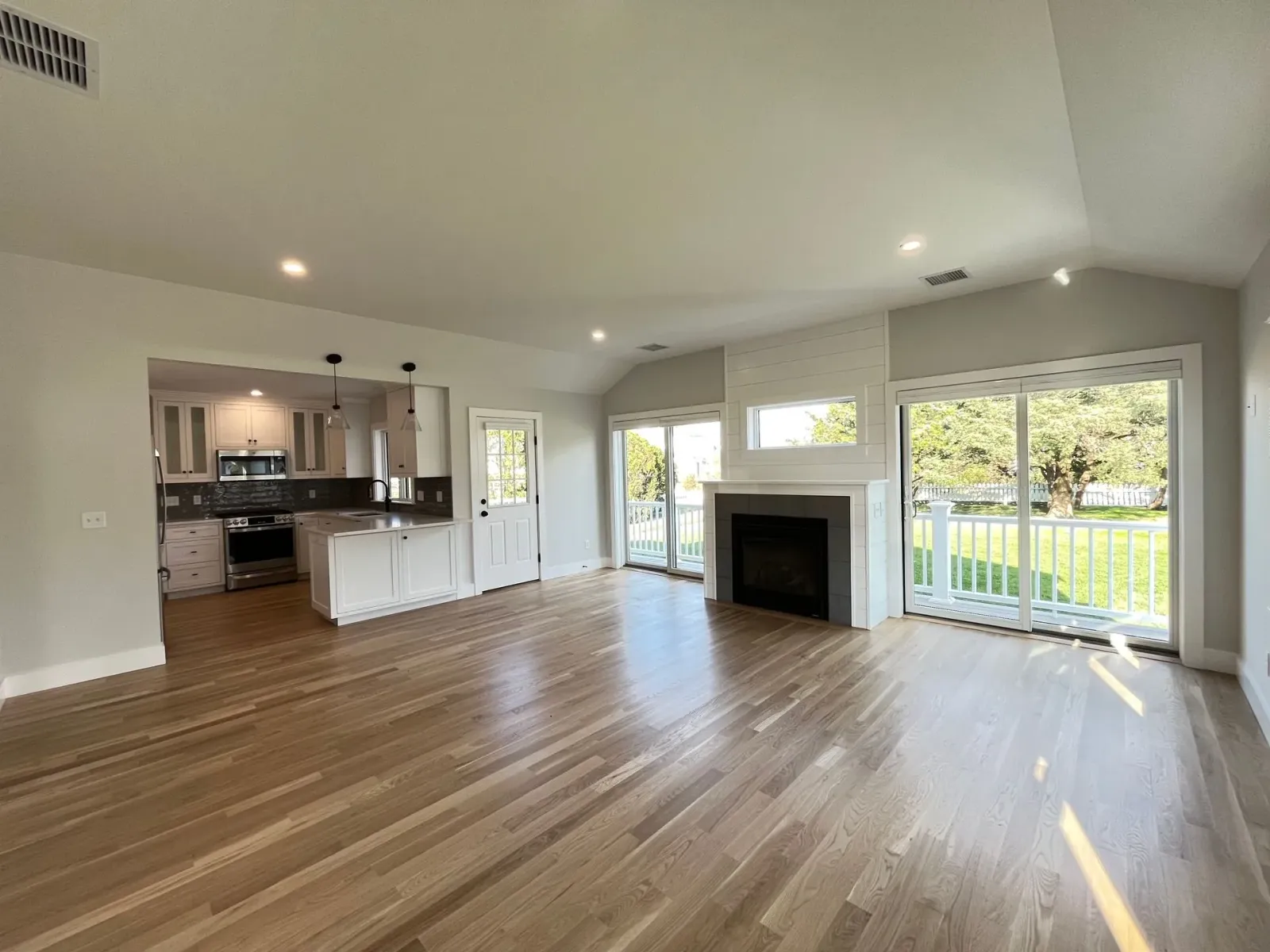 An empty living room with hardwood floors and a fireplace