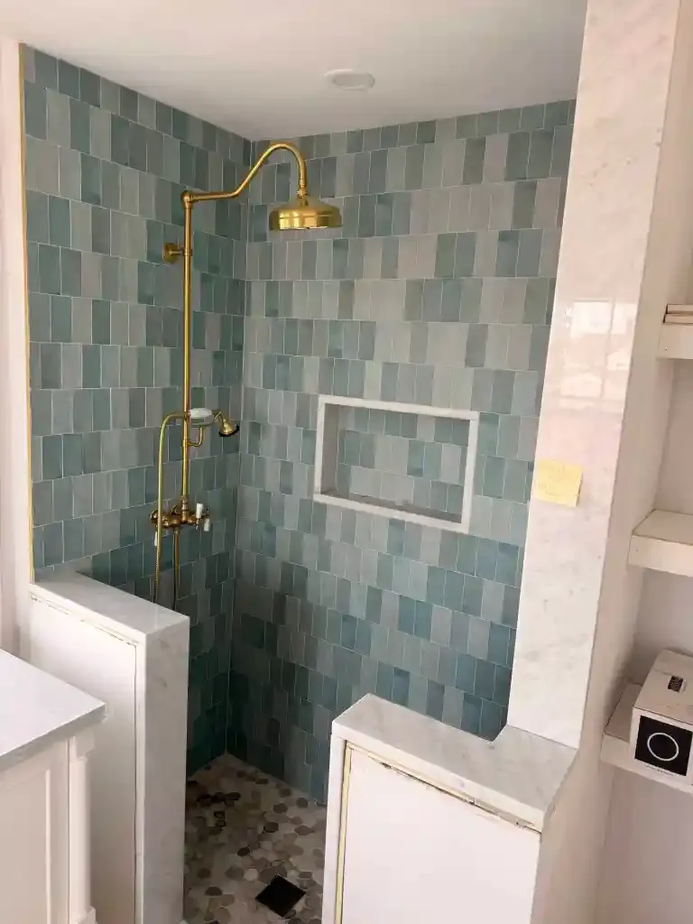 Contemporary shower with gold fixtures and blue tile walls.