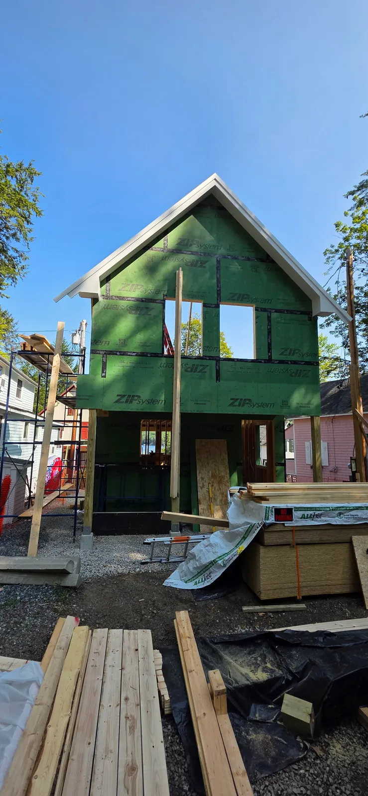 Framing stage of a two-story home build with green sheathing in the Lakes Region of New Hampshire