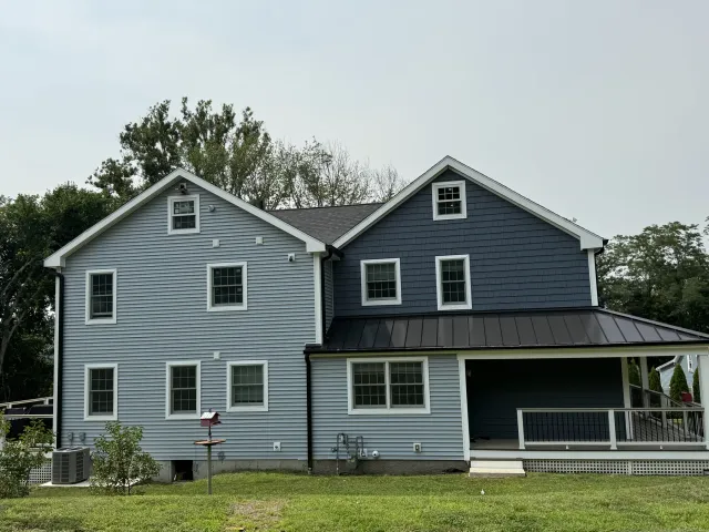 Rear of a newly built home with gray siding, black windows and a covered porch
