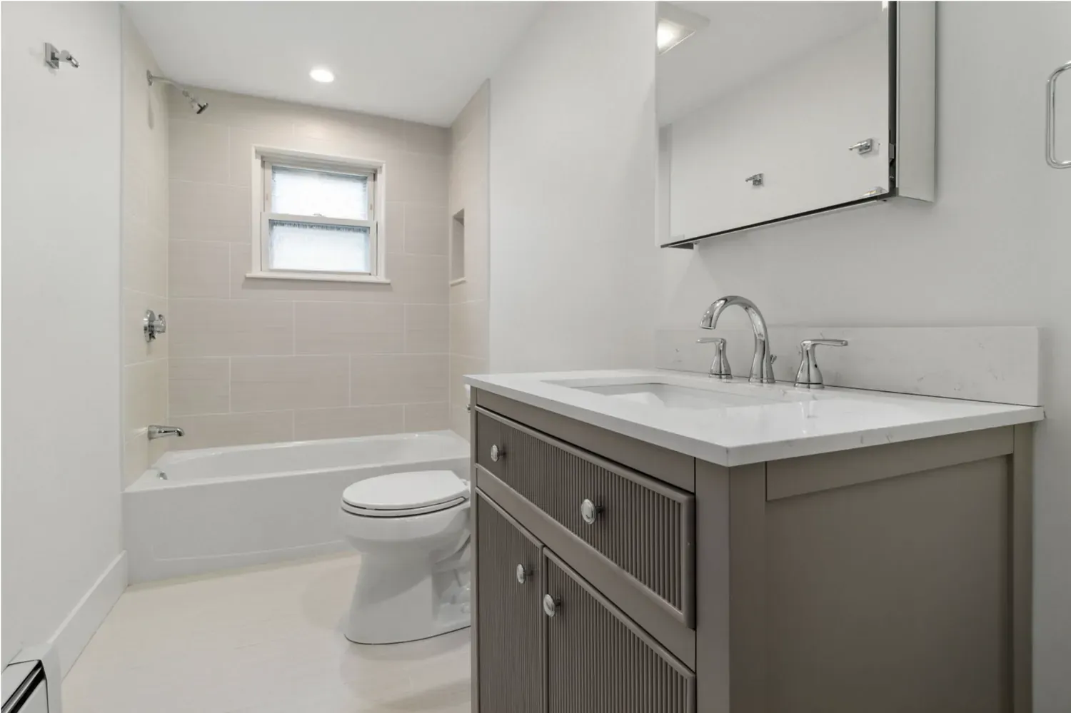 Bathroom renovation with tiled tub surround and quartz vanity