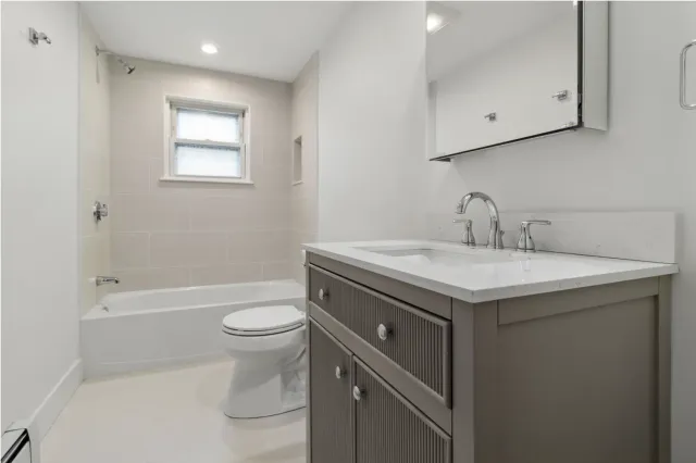 Bathroom renovation with tiled tub surround and quartz vanity