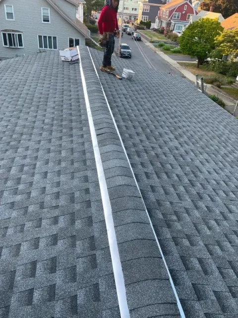 A man is standing on the roof of a house.