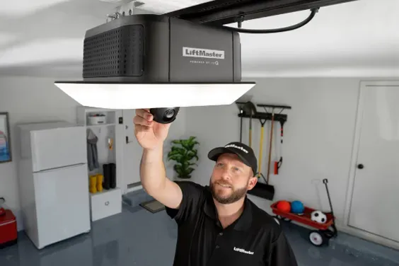 A man is installing a garage door opener on the ceiling.