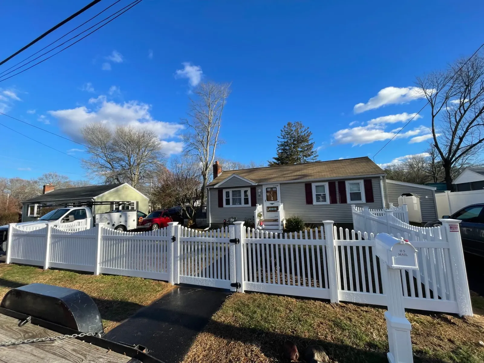 A gray house with white picket fence under a partly cloudy sky.