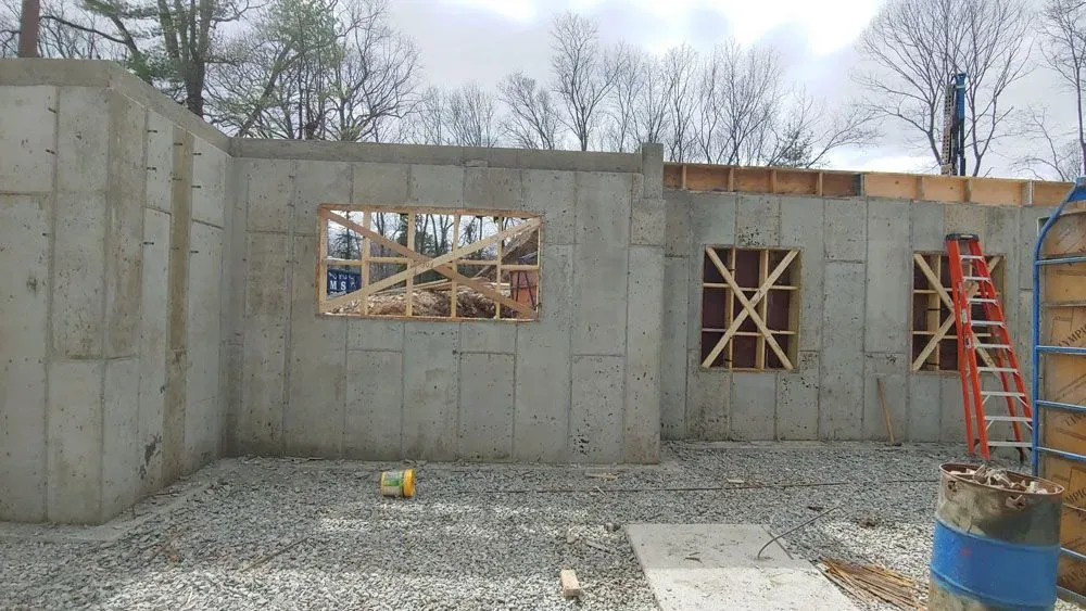 A concrete wall with a ladder in the background is being built.