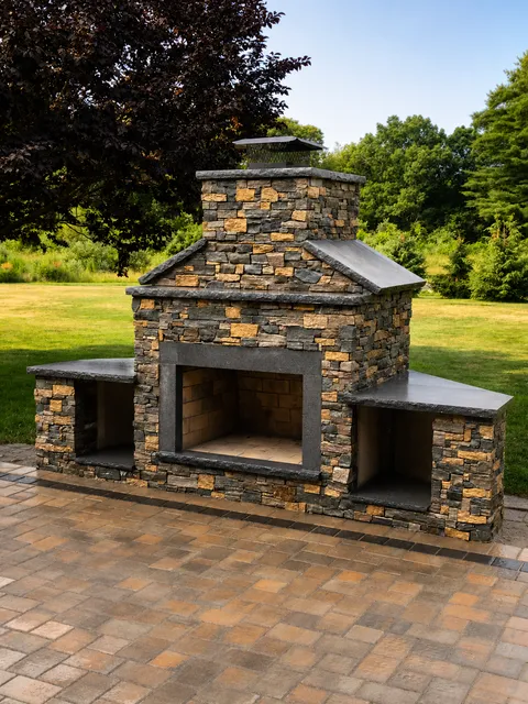 Custom outdoor stone fireplace with dark capstones and paver patio