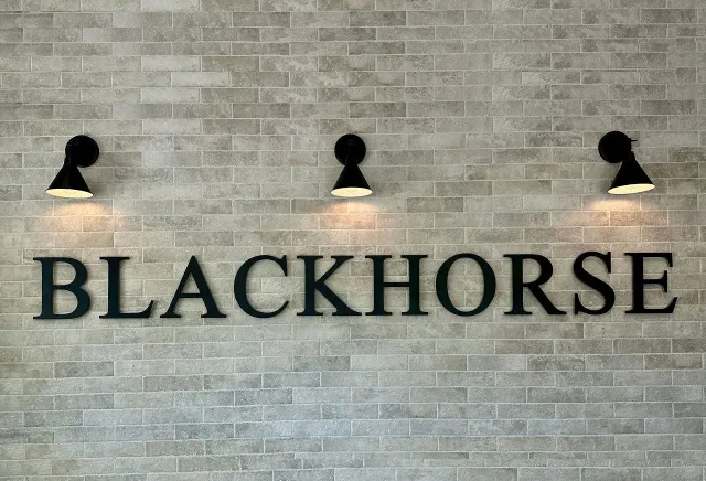 A sign on a brick wall that says blackhorse